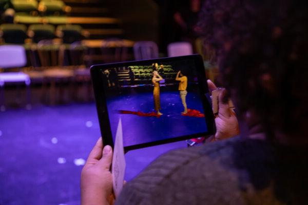 An audience members uses an iPad to watch virtual 舞者 perform on-stage in Glaize Studio 剧院
